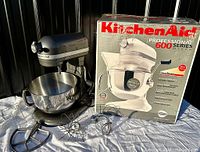 Mixer with bowl and three attachments displayed beside original box