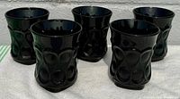 Five black glass tumblers arranged together, showing overall shape and design.