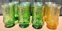 Set of 8 vintage Anchor Hocking Rainflower glasses, six in avocado green and two in amber, showing textured surface and no damage.