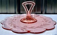 Side angle view of the pink depression glass serving platter showing the etched leaf pattern and raised handle
