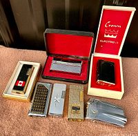 Full group of seven vintage refillable gas lighters displayed together, including box packaging