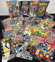 Overhead view showing 23 vintage Justice League comics spread out, all sleeved, featuring varied cover art from the 1990s including Justice League Europe titles.