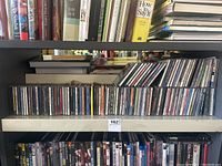 Wide view of two shelves showing rows of CDs in jewel cases, front and side visible with various artists and titles.