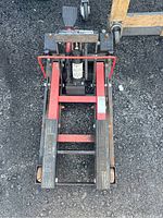 Top-down view showing the foot pedal pump, two long foot platforms with grip pads, and red safety bars.