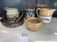 Five pottery vessels shown together on a surface: two pitchers, a small bowl, a vase, and a bowl with abstract design