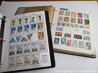 Photos of vintage stamps mounted on pages inside the binders, showing a variety of stamps from world countries with images of historical and cultural themes.