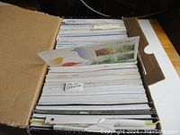Top view of unopened large shoe box containing neatly sorted and stacked First Day Covers from 1993 to 2003, with visible subject divider labels like '97-99 Definitive'.