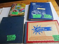 Four stamp albums arranged on a wooden surface showing their covers and labels