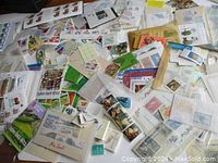 Overview of numerous envelopes, strips, singles, packs, blocks of world mint postage stamps and material scattered on surface