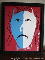 Front view of framed canvas painting showing horned mask face