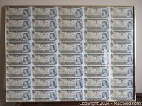 Full front view of framed sheet of uncut one dollar bills.