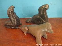 Three vintage Inuit seal carvings on wooden surface against a blue background