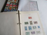 Photo showing opened pages of black 3-ring binder with Canadian stamps mounted on a page labeled 'Canada'