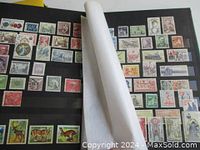 Open page of one album showing a variety of colorful stamps mounted on black pages.