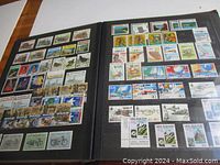 Open album showing double-sided pages filled with color New Zealand stamps featuring landmarks, flora, fauna, and historical themes
