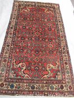 Full view of the rectangular Persian Mashad rug showing the detailed red field with geometric and floral motifs, bordered by a multicolor frame.