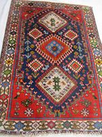 Full top view of rug showing three central diamond medallions, red border and multicolor geometric motifs