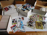 Three white cardboard boxes filled with hockey cards and loose sleeved cards