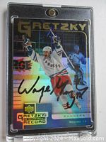 Front of Wayne Gretzky 1999 Upper Deck hockey card with holographic design and black autograph, in a clear protective one-touch magnetic card holder.