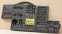 Opened black plastic case showing 123 piece tool set including various drill bits, hole saws, augers, and nut drivers arranged in molded compartments.