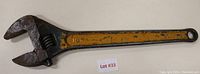 Full view of the 18-inch adjustable wrench showing the worn yellow and green painted handle and adjustable jaw.