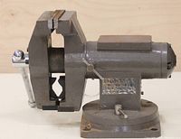 Front-left side view of gray Torin vise showing clamp jaws, swivel base, and anvil surface.