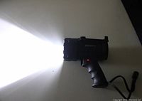 Black Dorcy rechargeable handheld spotlight turned on showing bright light beam