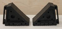 Pair of black rubber wheel chocks shown side by side with triangular shape and handles visible.
