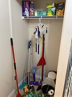 Image showing various cleaning tools including broom, mop, dustpan, buckets, and other accessories on floor and hanging on wall.