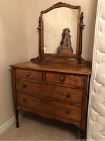 Front view of dresser showing two small upper drawers, two large lower drawers, and attached framed mirror with turned wood supports.