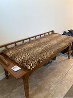 Hall bench with leopard print cushions and hardwood frame, showing wood finish and spindle backrest on the side