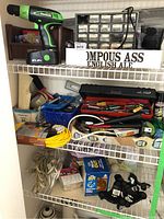 Wide view of shelves showing Kawasaki drill, hardware organizer, extension cords, tools, and various hardware supplies.