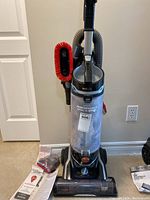 Full view of Hoover Swivel XL Pet Plus vacuum upright with clear dirt cup, hose, and red brush attached on side.