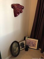 Overall view of the plaster bust sculpture mounted on wall above the corner arrangement of framed prints and busts on floor, showing group composition.