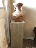 Vase and plinth shown together against wall, illustrating overall size and arrangement.