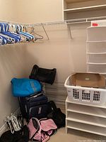 Photo showing assorted bags, two-piece luggage set, shoe racks, laundry basket, and closet hanging caddy inside a closet.