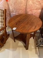 Round oak table viewed from a slightly above angle showing the top surface with visible wear and dark marks.