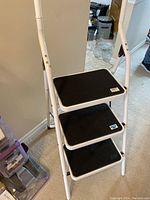 Front view of the 3 step folding ladder showing black non-slip steps and white frame