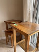 Three nesting tables arranged in corner; smaller table has broken leg, larger table shows wear