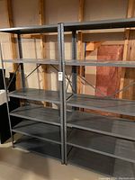 Front view of two metal shelving units placed side by side in basement storage area.