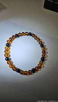 Top view of the maple colored AAA Baltic amber and dark bead stretchy bracelet laying flat on a white surface.