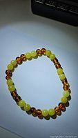 Photo of the stretchy bracelet showing alternating yellow lemon jade beads and translucent amber-colored beads on a white background