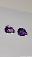 Pair of pear cut amethyst gemstones showing deep purple color.