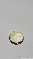 Round golden citrine cabochon gemstone with visible natural inclusions and polished surface, light golden color, approx 10.7mm diameter.