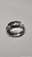 Photo of a clear oval cut natural quartz crystal gemstone on a plain background.