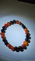 Full circular view of the natural gemstone bracelet showing red agate and silver sheen obsidian beads under ambient light.