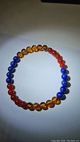 Top view of round polished red carnelian, lapis lazuli, and golden Baltic amber beads strung on a stretchy bracelet.