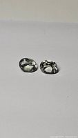Two oval cut light teal green amethyst prasiolite gemstones on white background, showing facets and color tone