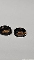 Two oval cut smokey quartz gemstones side by side, showing their matching cut and color.