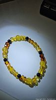 Photo of the rare Baltic amber stretchy bracelet composed of gradient honey, golden, and maple amber beads with black onyx accents, arranged in a circular shape on a plain background.